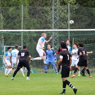 En fotbollsmatch där spelare hoppar för att nicka bollen mot mål.
